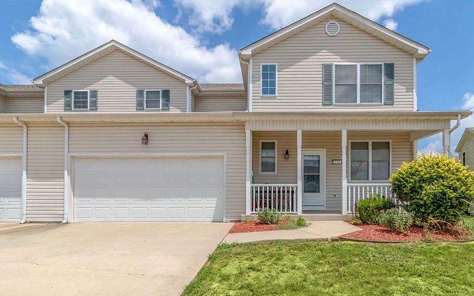 a beige house with a garage door and a lawn