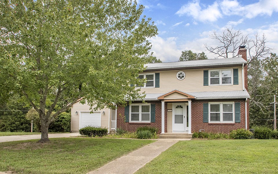 a small brick house with a tree in front of it