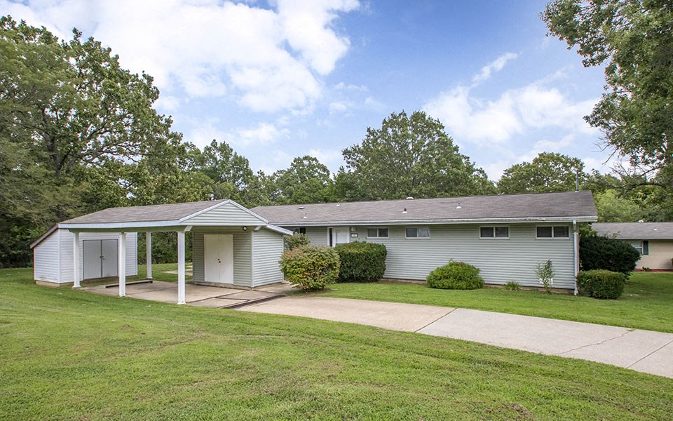 a small white house with a driveway and a lawn