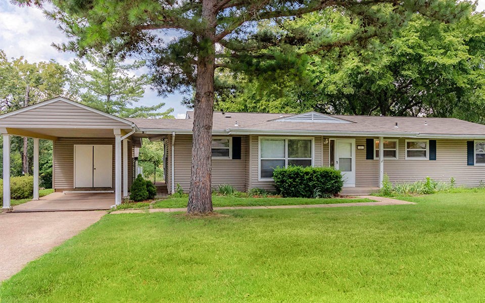 the front of a house with a yard and a tree