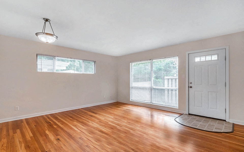 an empty living room with wood floors and a white door