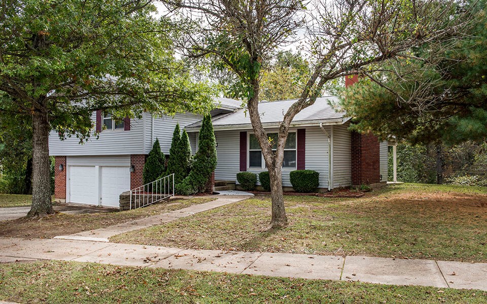 a white house with a sidewalk and trees