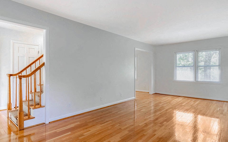 an empty living room with wood floors and a staircase