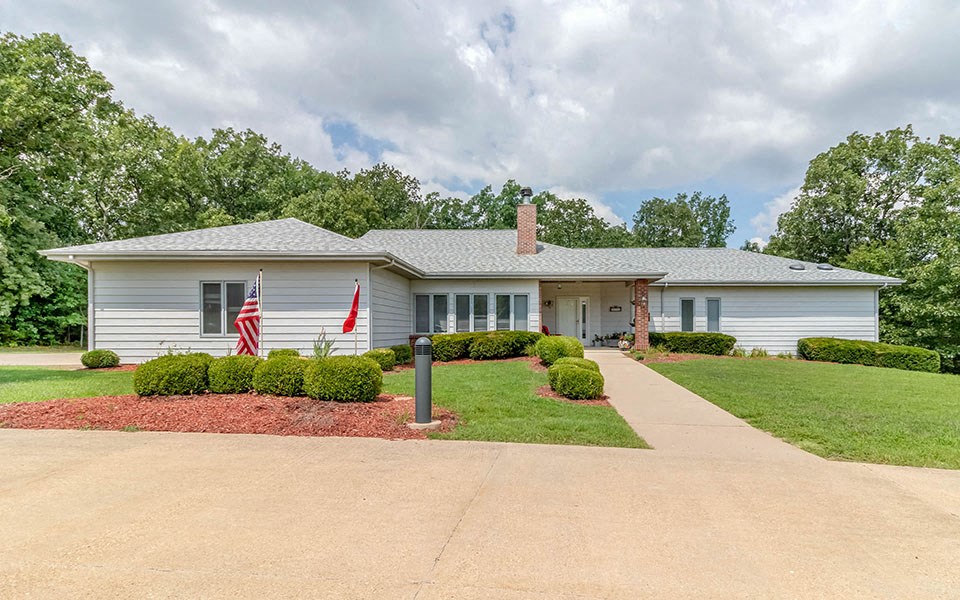 a white house with an flag and a driveway