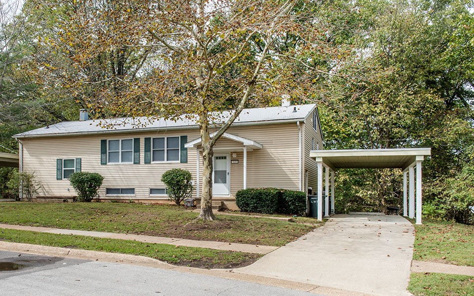 a beige house with a covered porch and a sidewalk