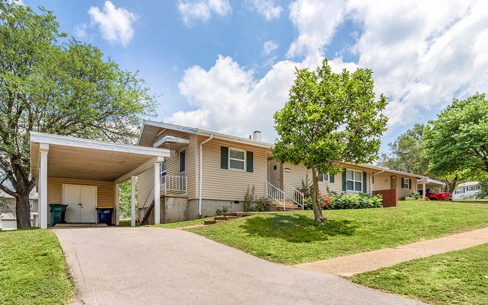 the front of a house with a driveway and a tree