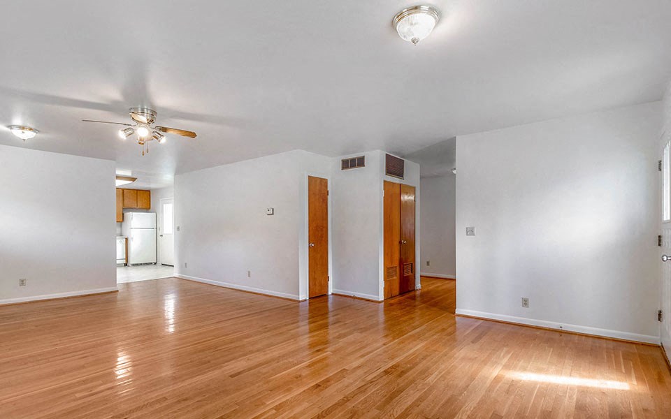an empty living room with white walls and wood floors