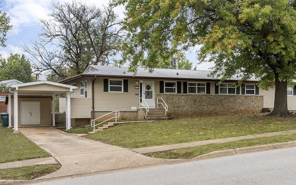 the front of a house with a driveway and a tree