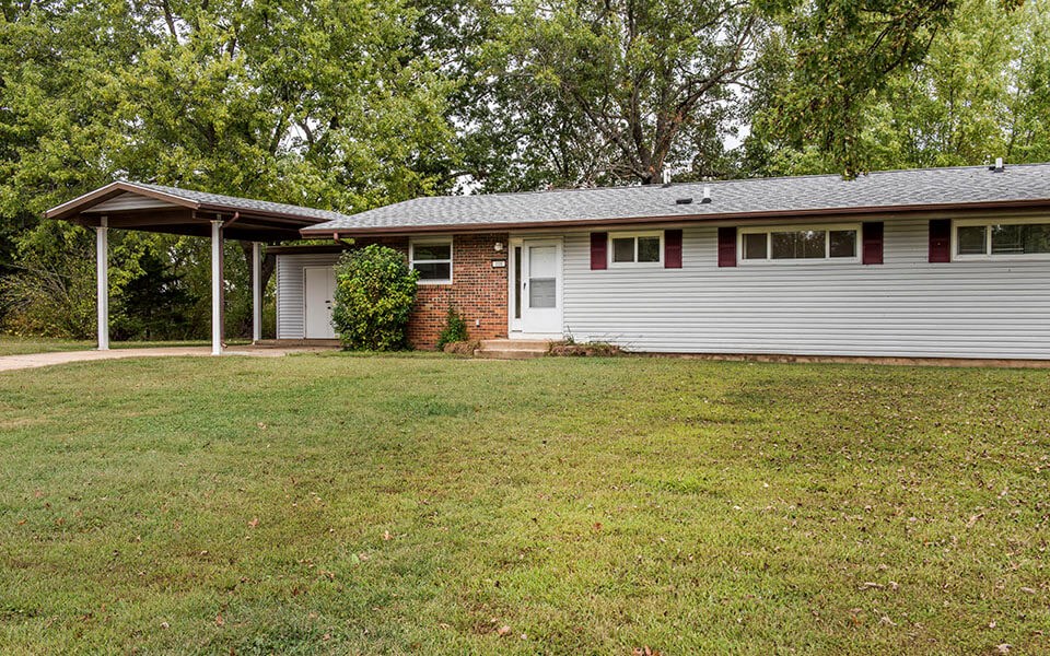 a white and brick house with a grassy yard in front of it