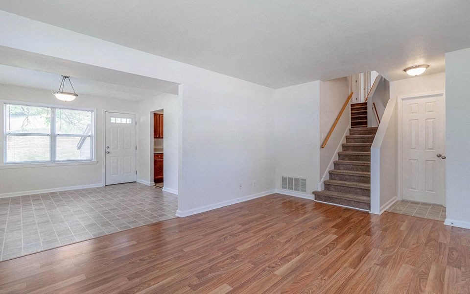 an empty living room with hard wood floors and a staircase