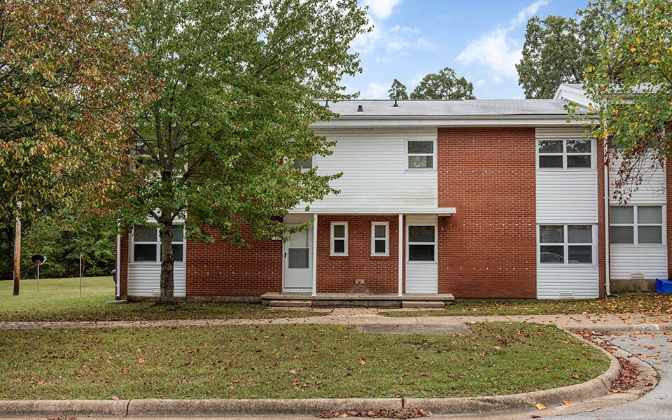 the front of a brick and white building with trees