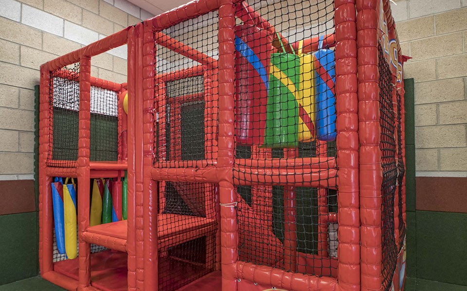 a playground with a red cage with toys in it