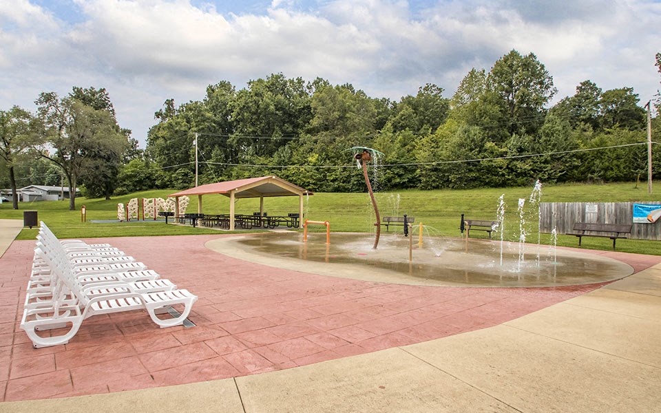 a park with a fountain and white benches