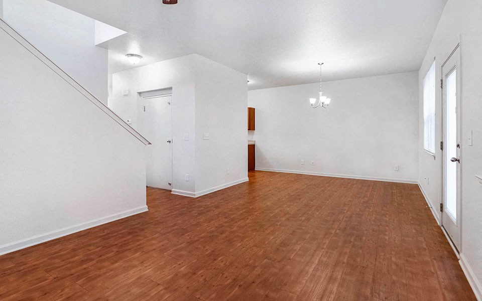 an empty living room with wood floors and white walls