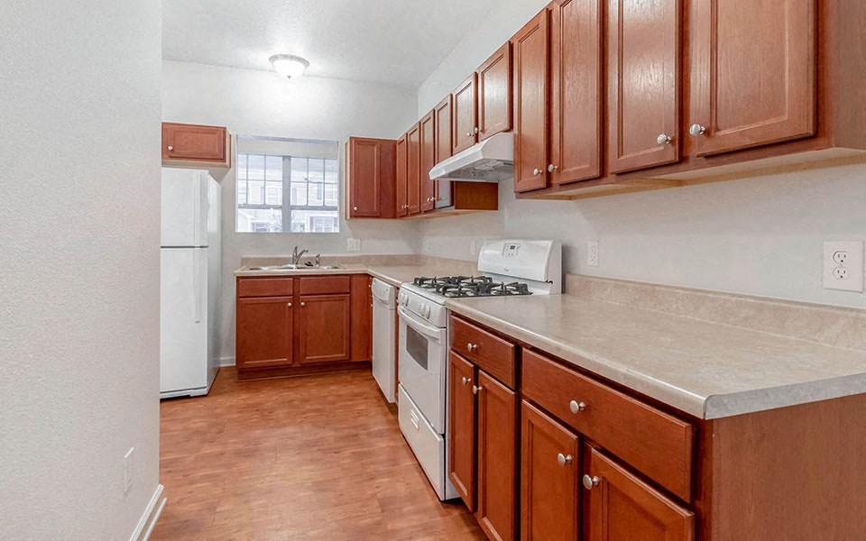 an empty kitchen with wooden cabinets and white appliances