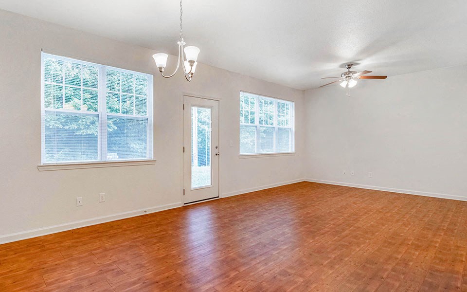 an empty living room with a wooden floor and a ceiling fan