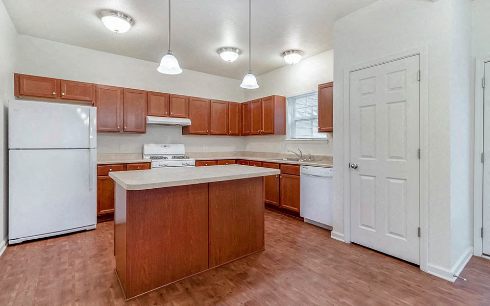 an empty kitchen with wooden cabinets and white appliances