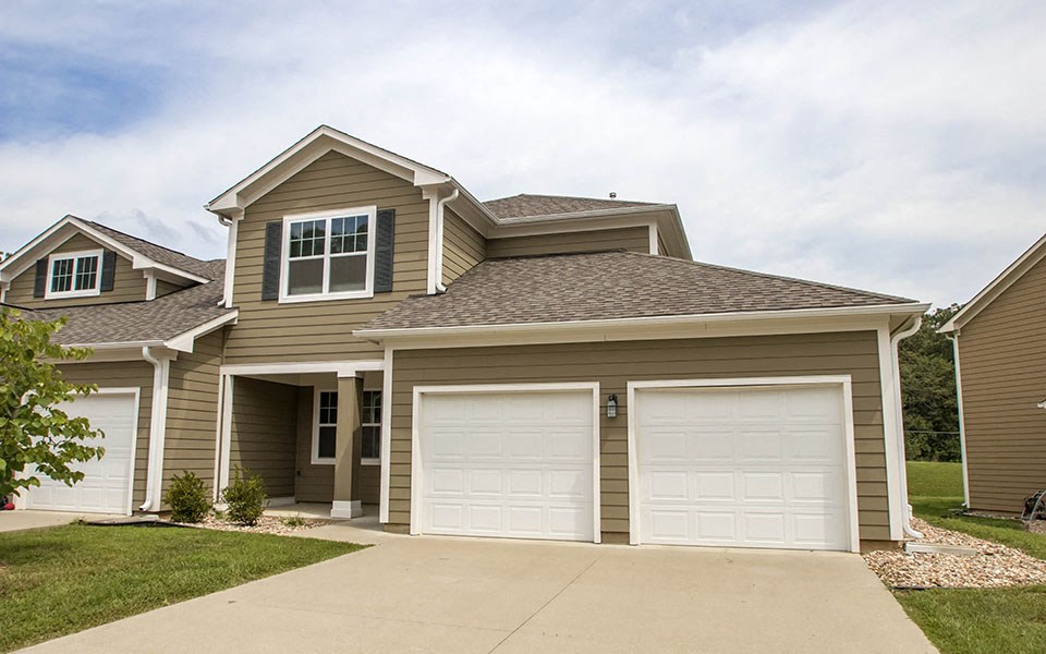 a brown house with two garage doors
