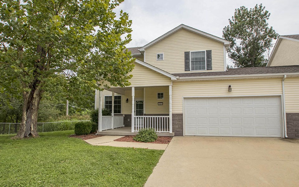 a yellow house with a driveway and a white garage door