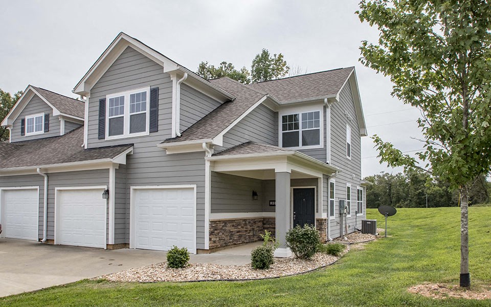 a gray house with white garage doors and a lawn