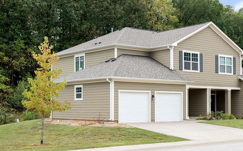 a tan house with two garage doors