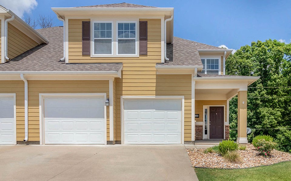a yellow house with two garage doors in front of it