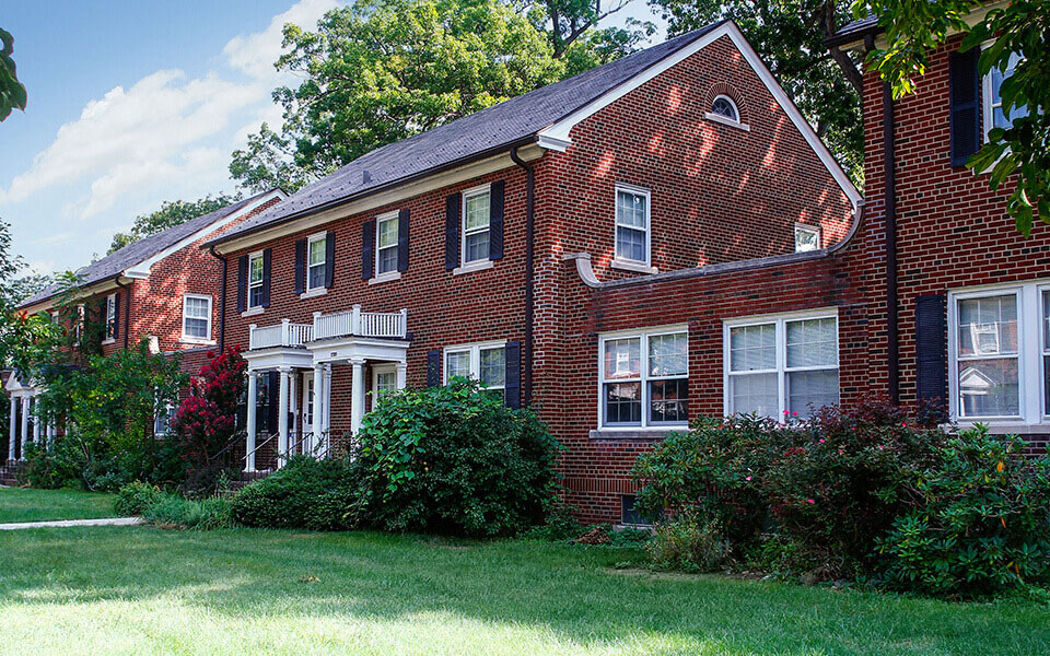 a red brick house with bushes in front of it