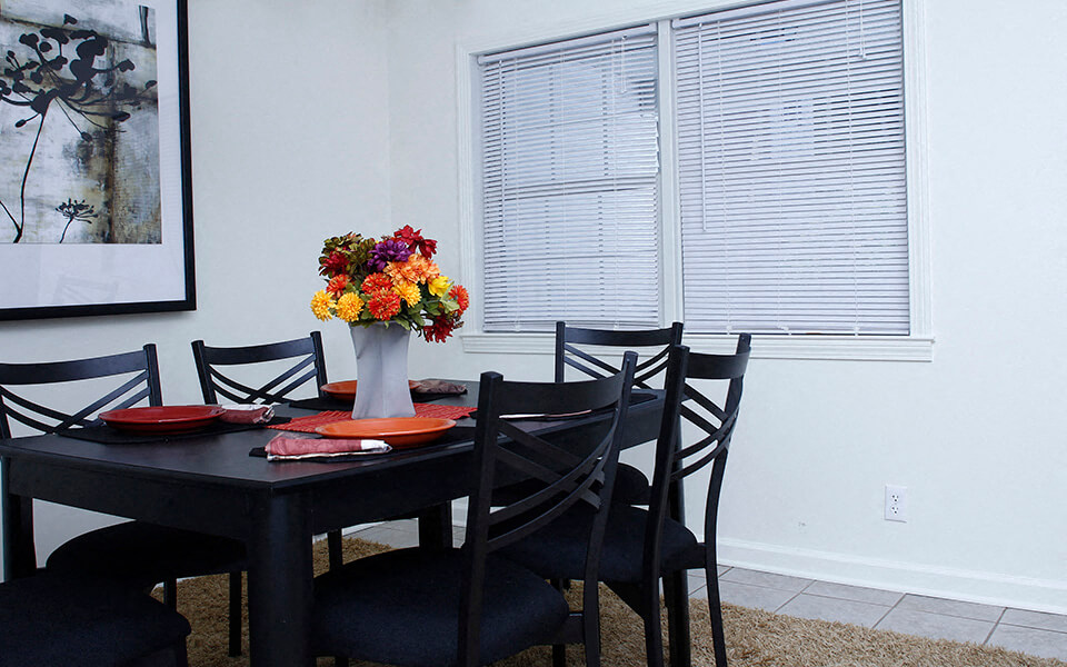 a dining room with a table and chairs and a vase of flowers