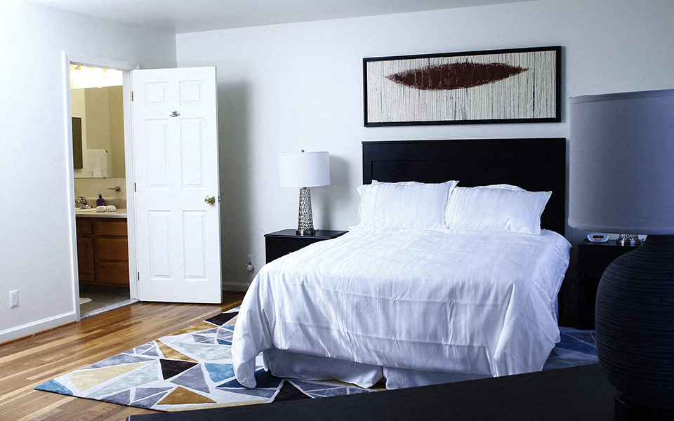 a bedroom with a white bed and a bathroom