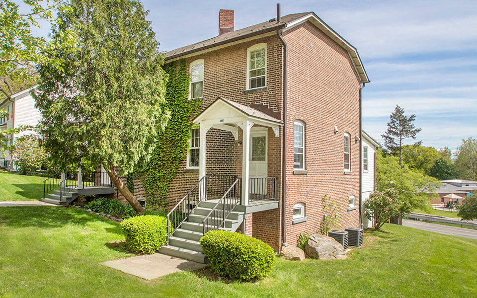 the front of a brick house with stairs and a tree