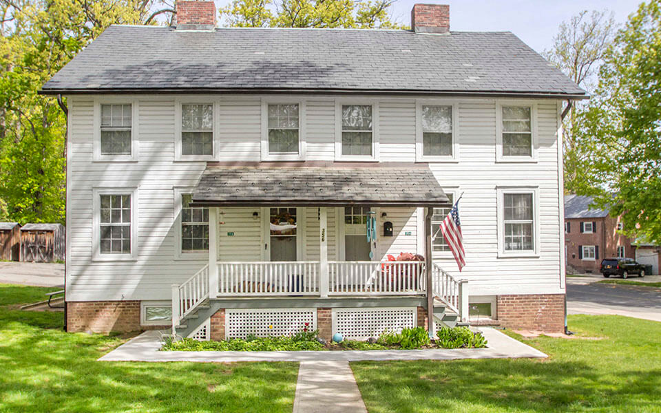 a white house with a porch and an flag
