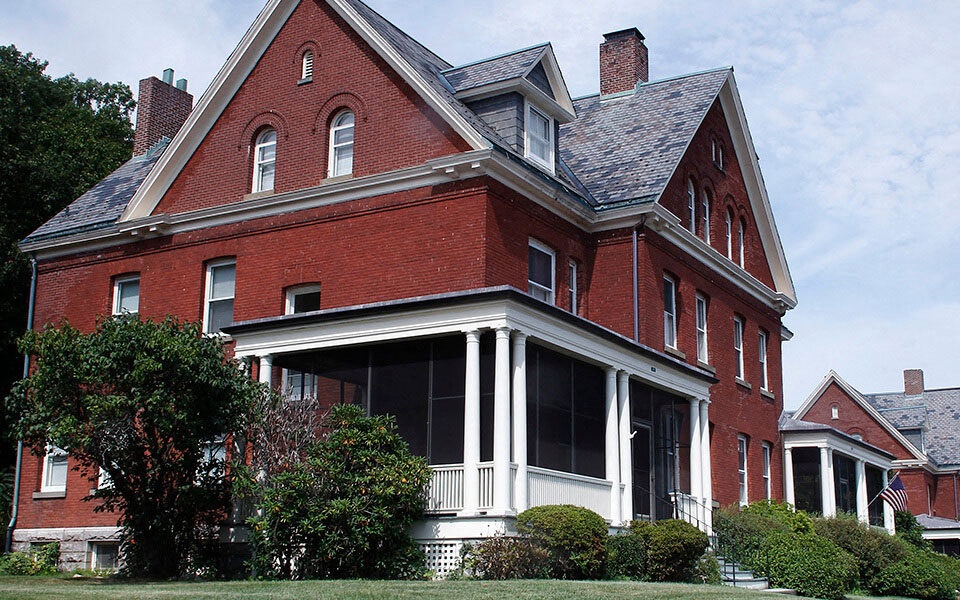 a red brick house with a porch and a black roof