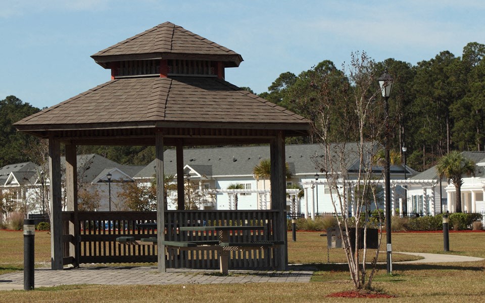 a gazebo in a park with houses in the background
