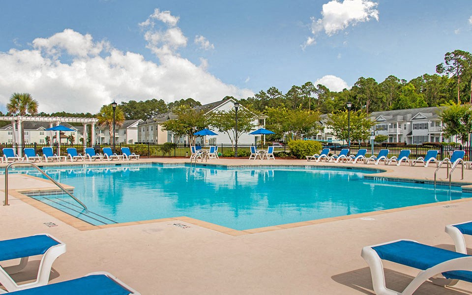 a large swimming pool with blue chairs around it