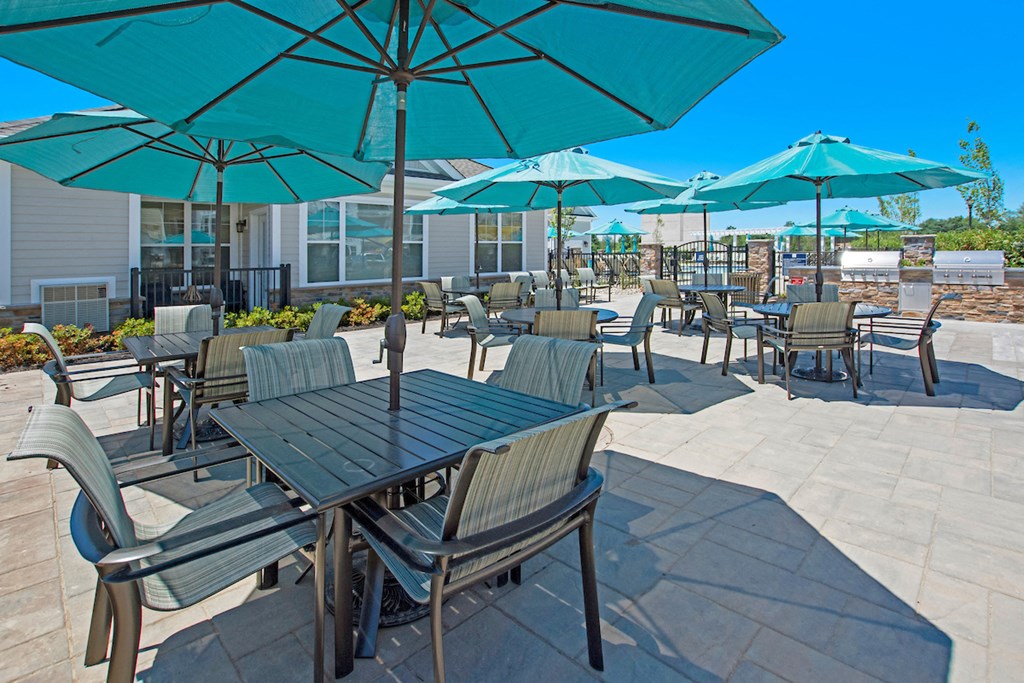 tables and chairs with umbrellas on the patio of a building