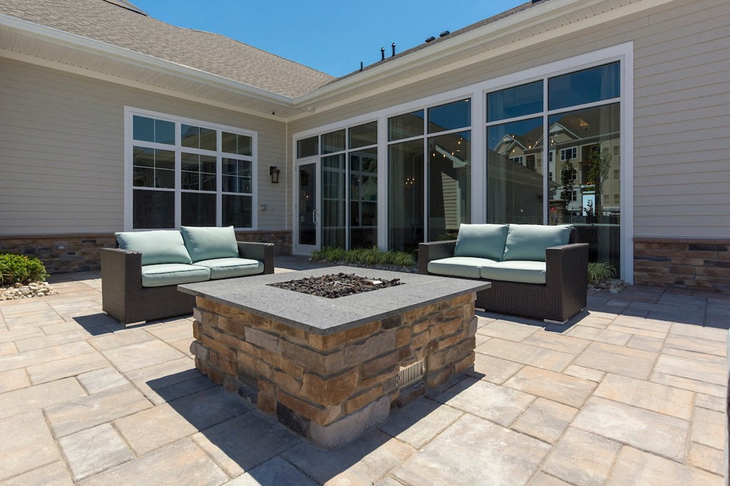 a patio with a firepit and chairs in front of a house