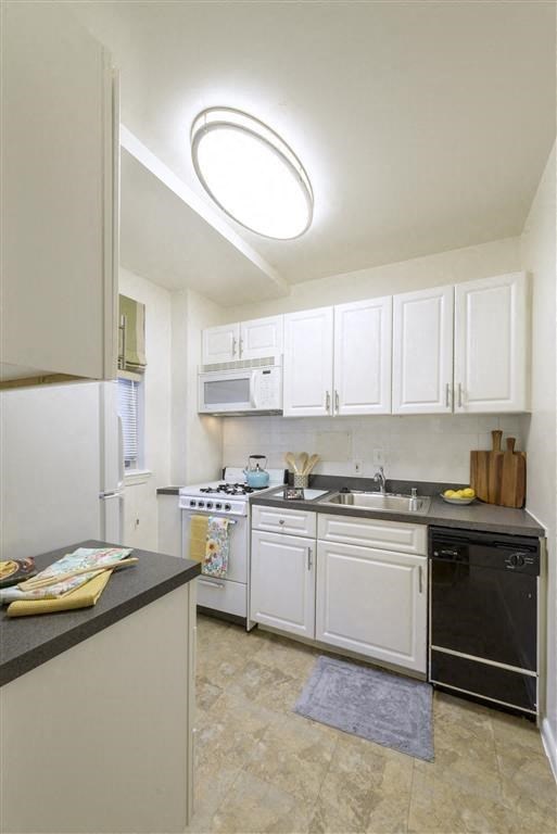 a kitchen with white cabinets and a black stove and a sink