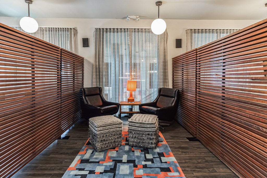 a lounge area with chairs and tables and a large window