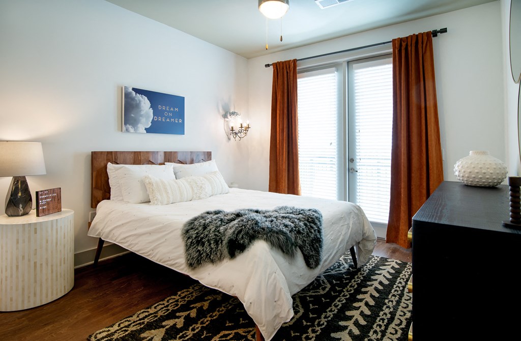 a bedroom with a bed and a large window and a rug