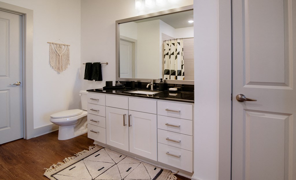 a bathroom with white cabinets and a toilet and a mirror