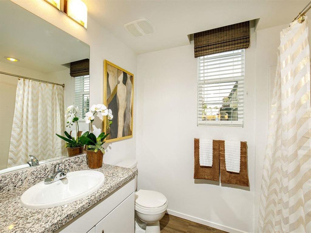 Bathroom with a window and glass mirror and a shower with a towel rack and sink