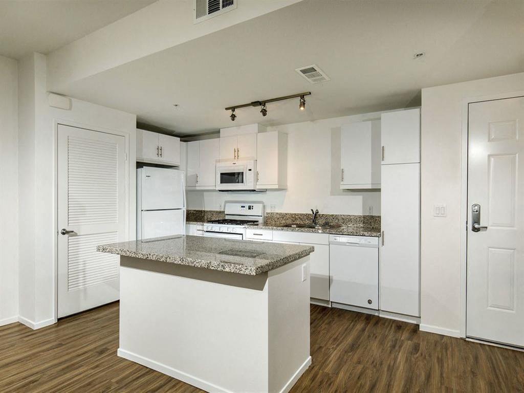 Spacious kitchen with an island and three lights on top of the ceilling