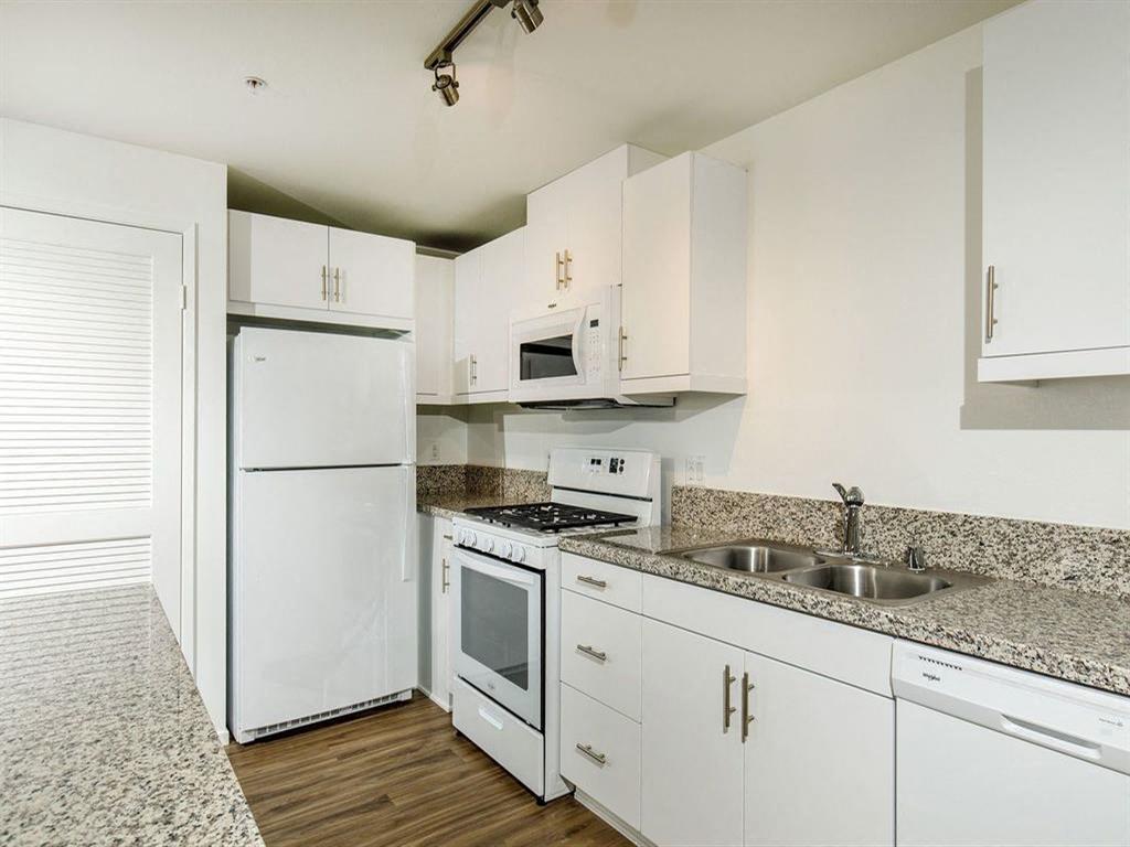 White cabinets with attached microwave on top of gas stove