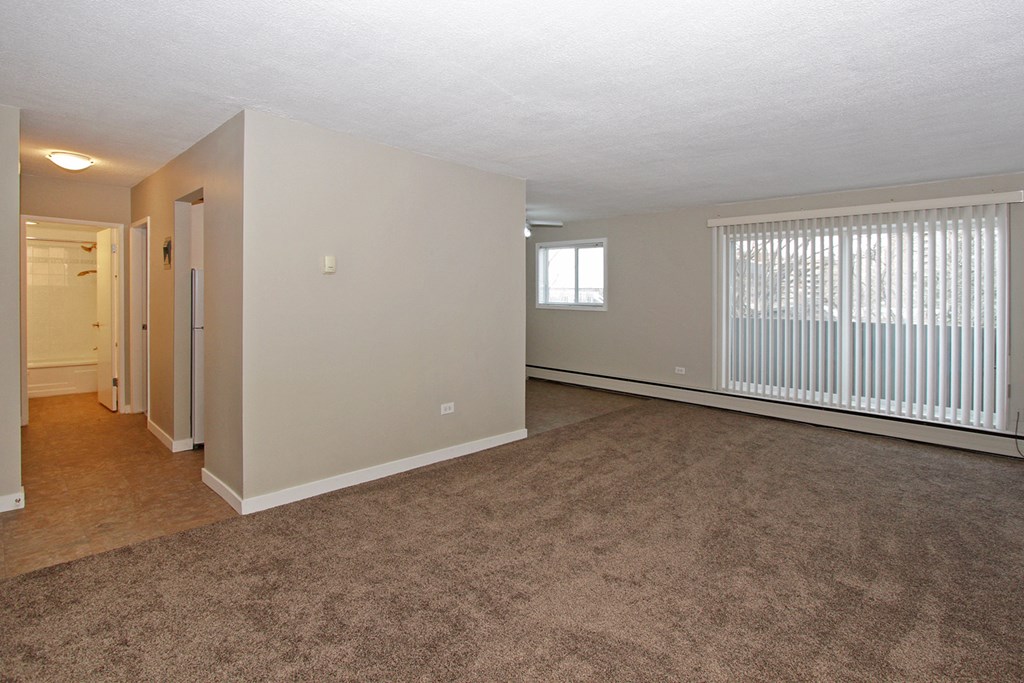 the living room and dining room of an apartment with a large window