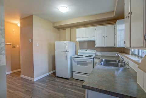 an empty kitchen with white appliances and stainless steel counter tops
