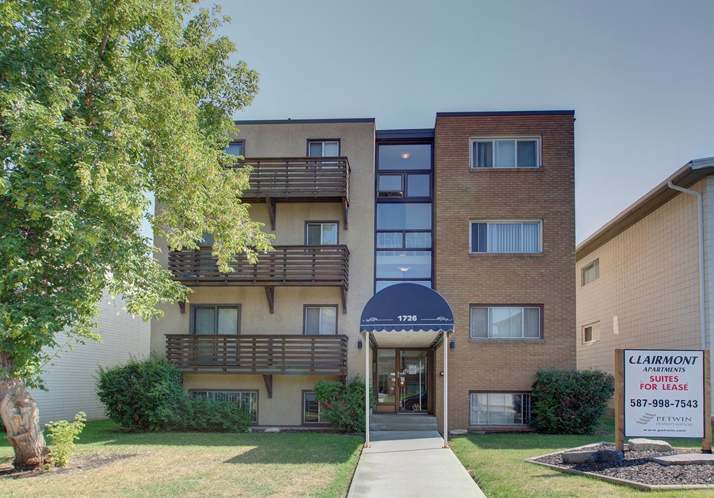 an apartment building with a sidewalk and a sign in front