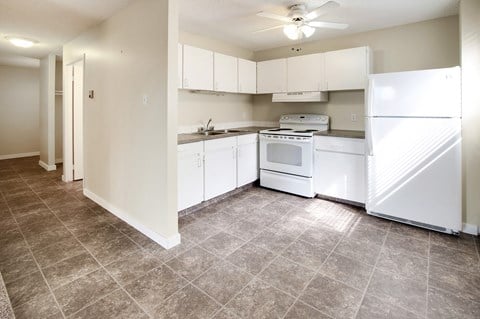 an empty kitchen with white appliances and white cabinets