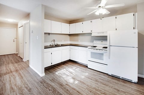 an empty kitchen with white appliances and white cabinets