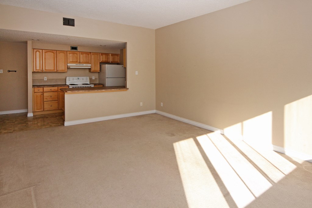 an empty living room with a kitchen in it