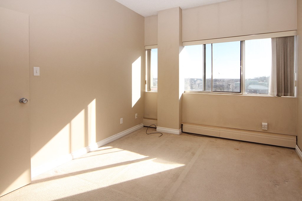 the living room of an empty apartment with large windows